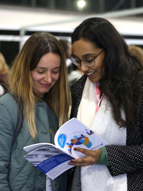 Two women look at the BSI Congress programme